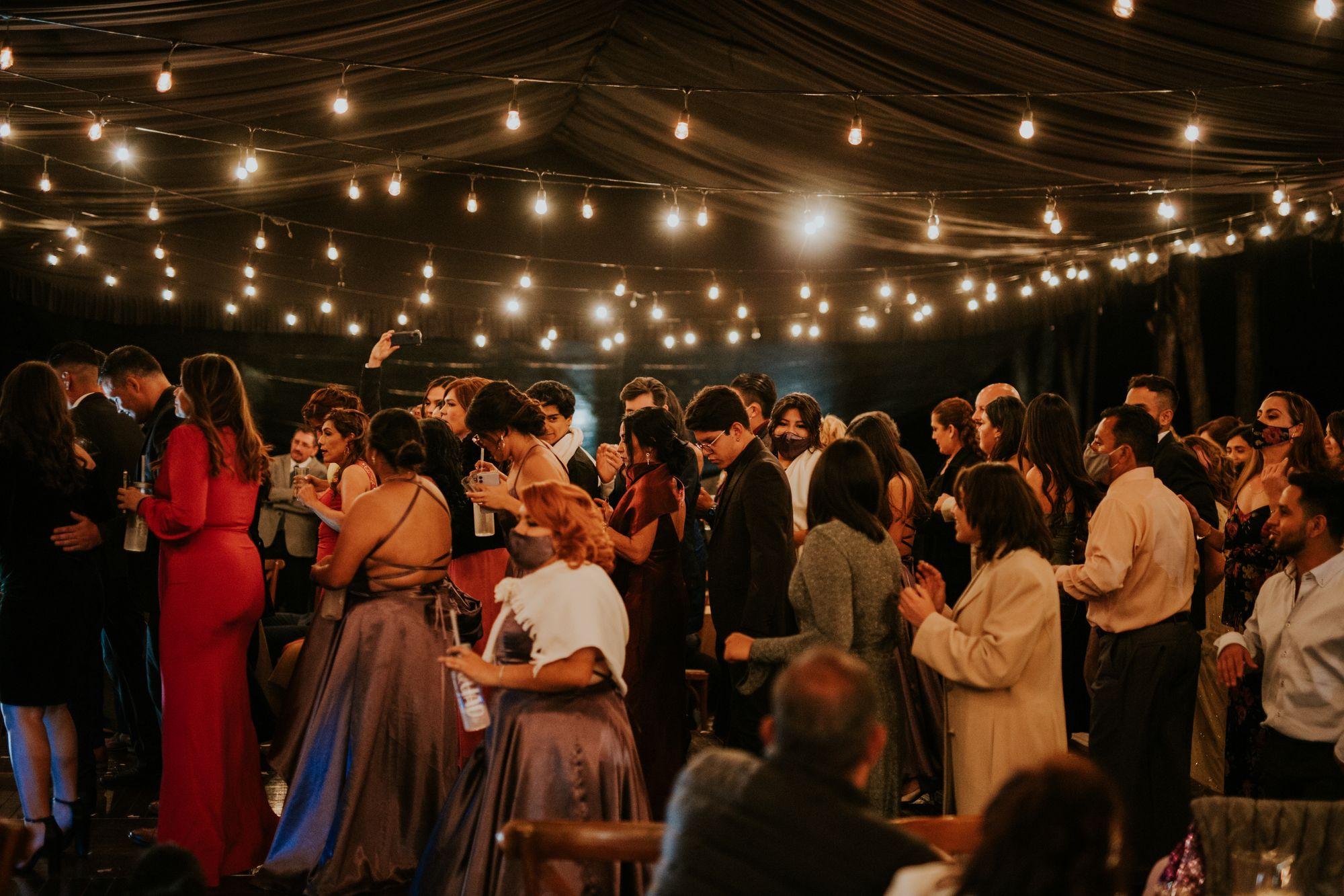 Well-dressed guests celebrating indoors under string lights.