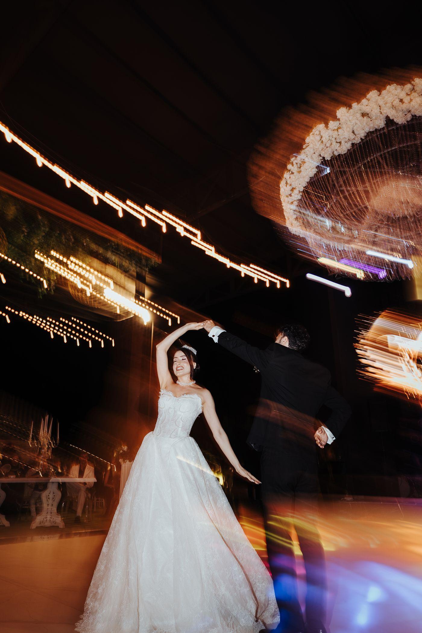A bride dancing beneath chandeliers, caught in motion.