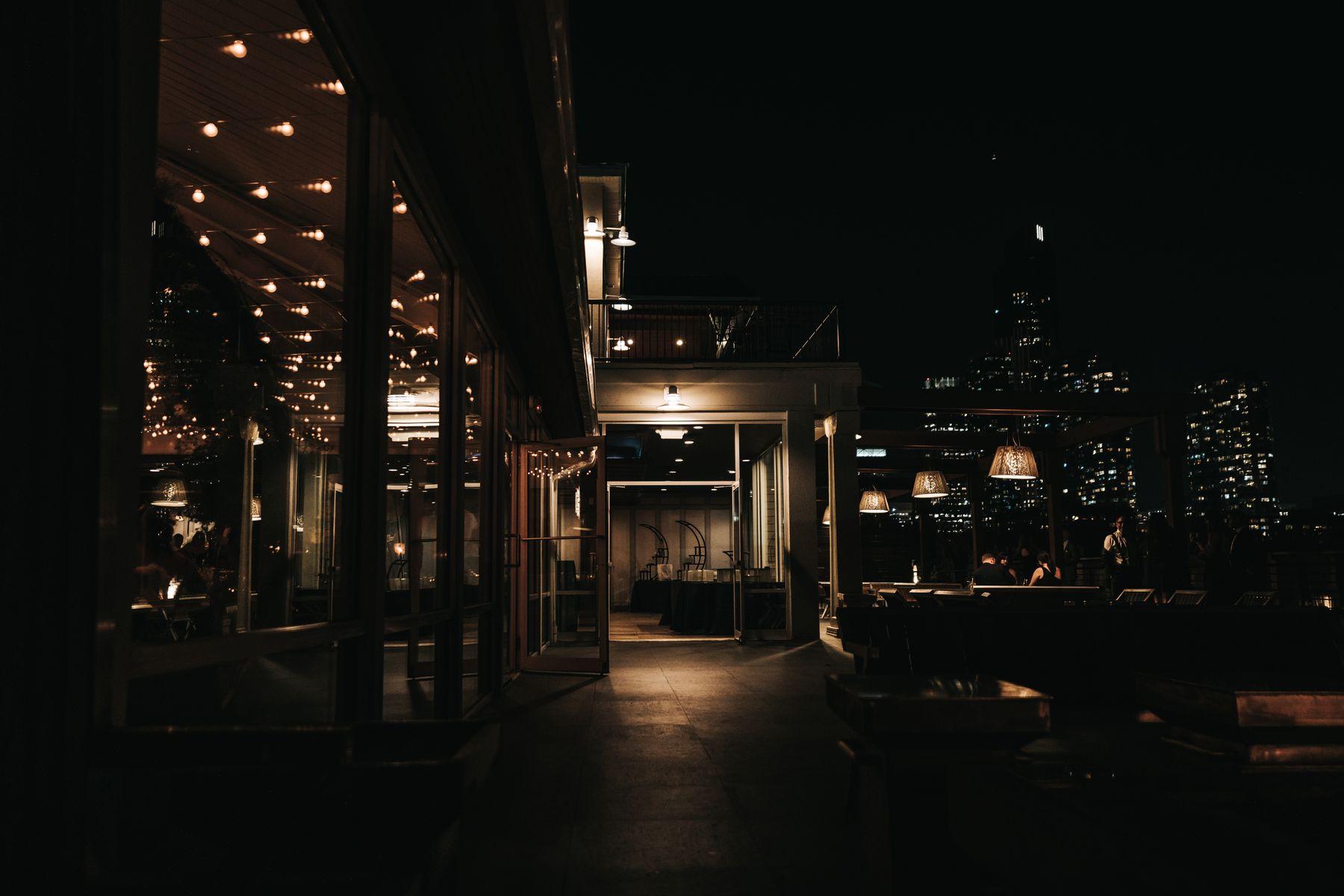 A rooftop bar at night with the city skyline beyond.