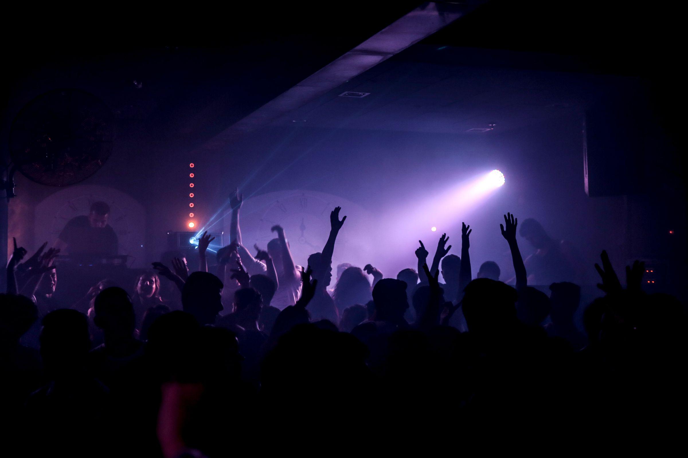 A dark room, a single beam of light and a crowd in silhouette.