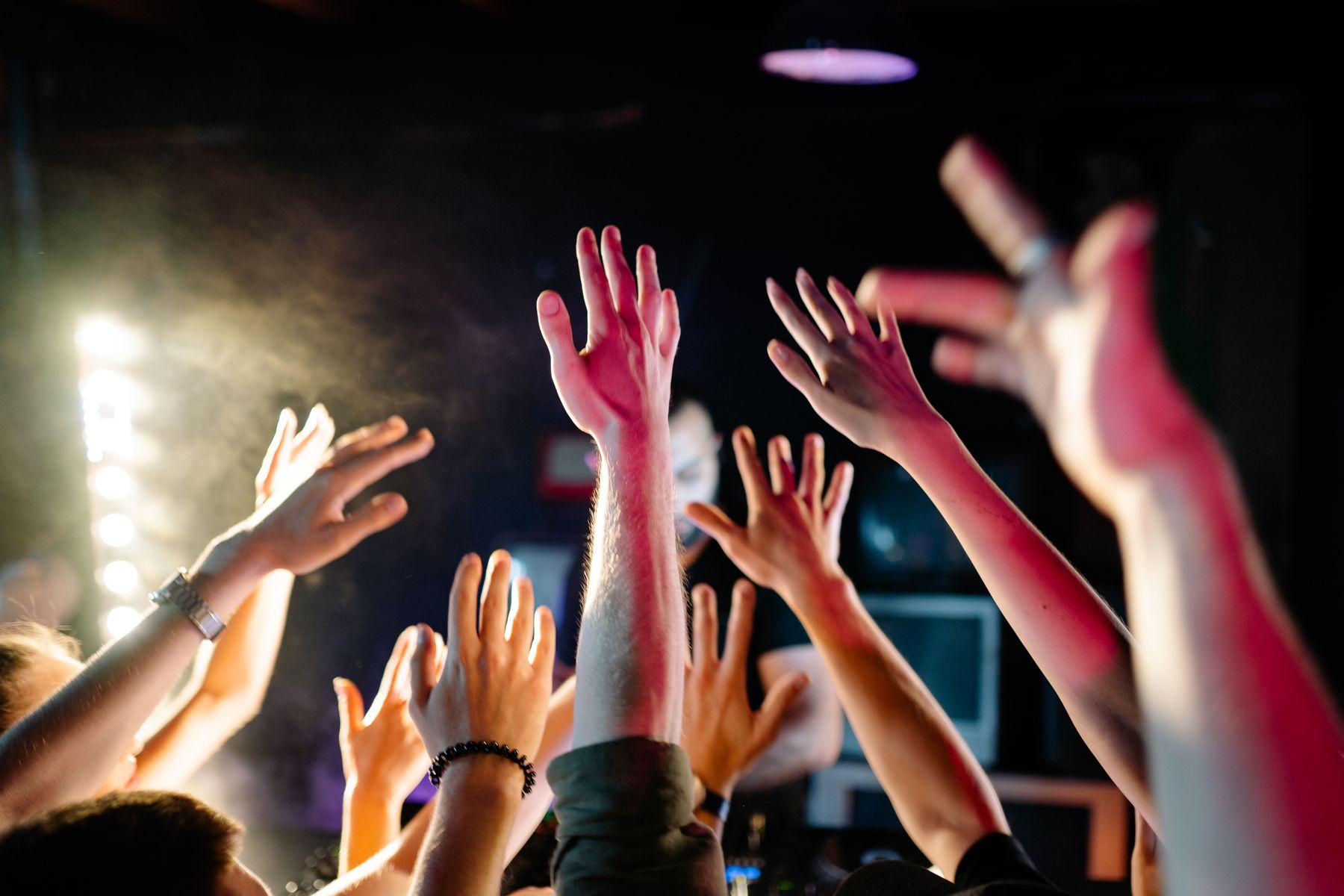 Hands raised under warm stage lights.