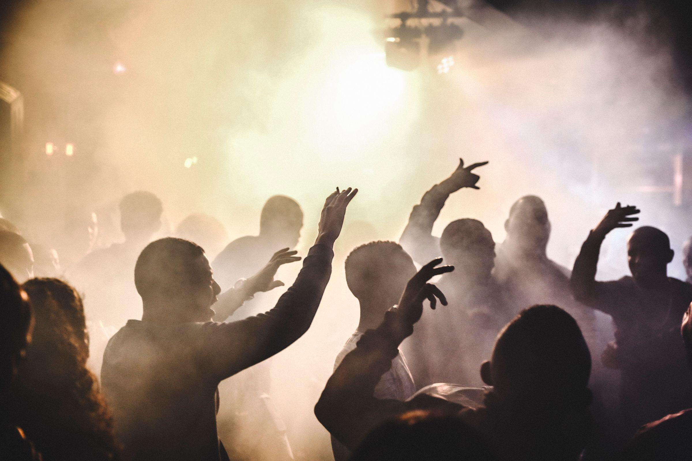 A crowd with hands raised under warm golden light.