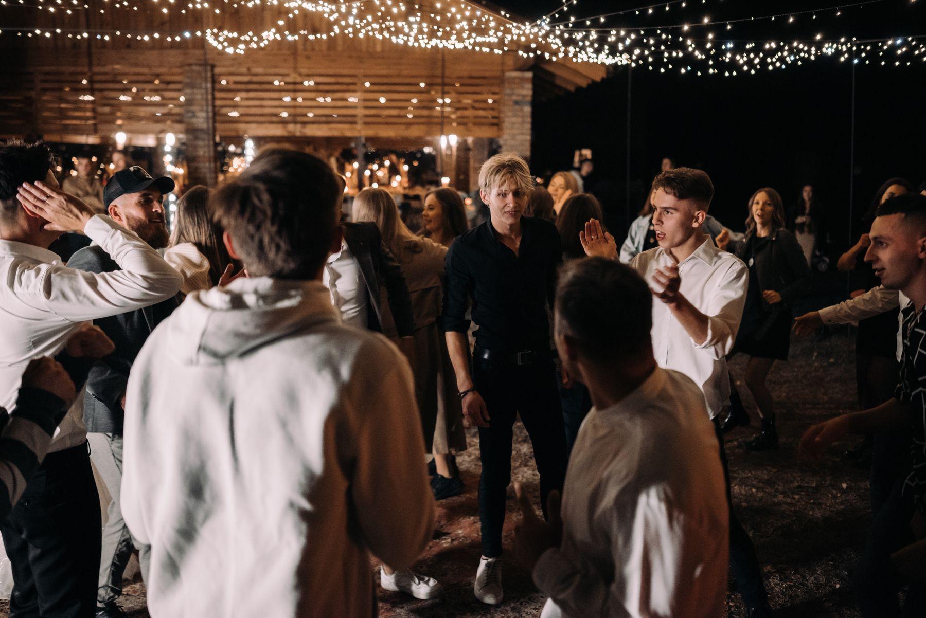Guests dancing under string lights at an evening reception.