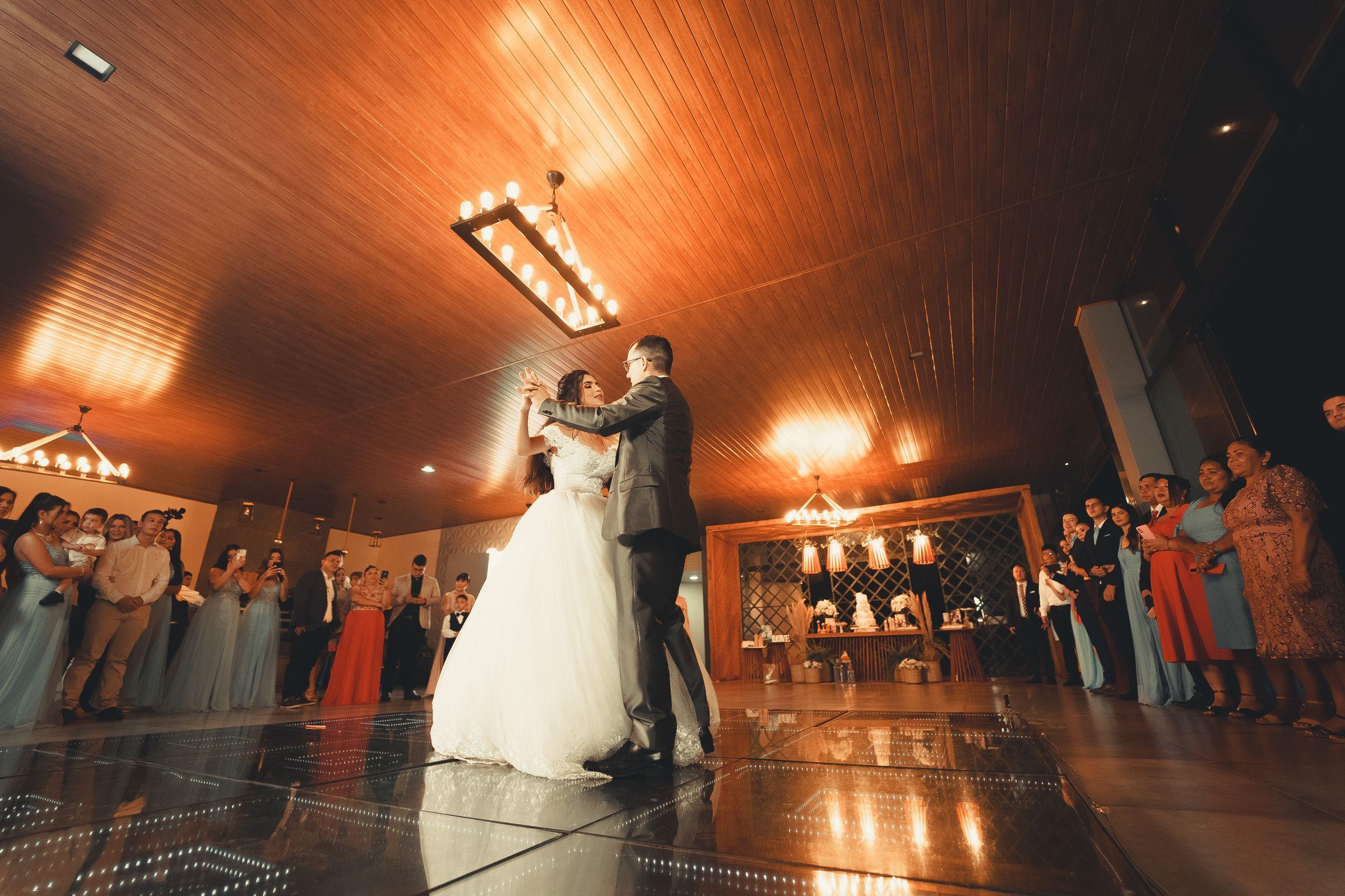 A couple's first dance in a warmly lit venue, surrounded by guests.